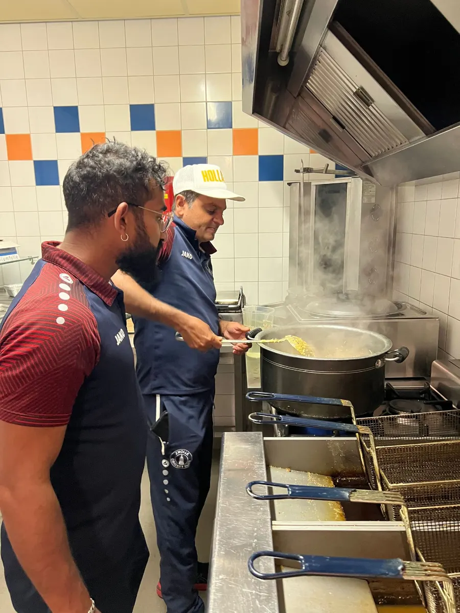 Home Twee leden van Cricket Club Zwolle koken samen in de clubkeuken